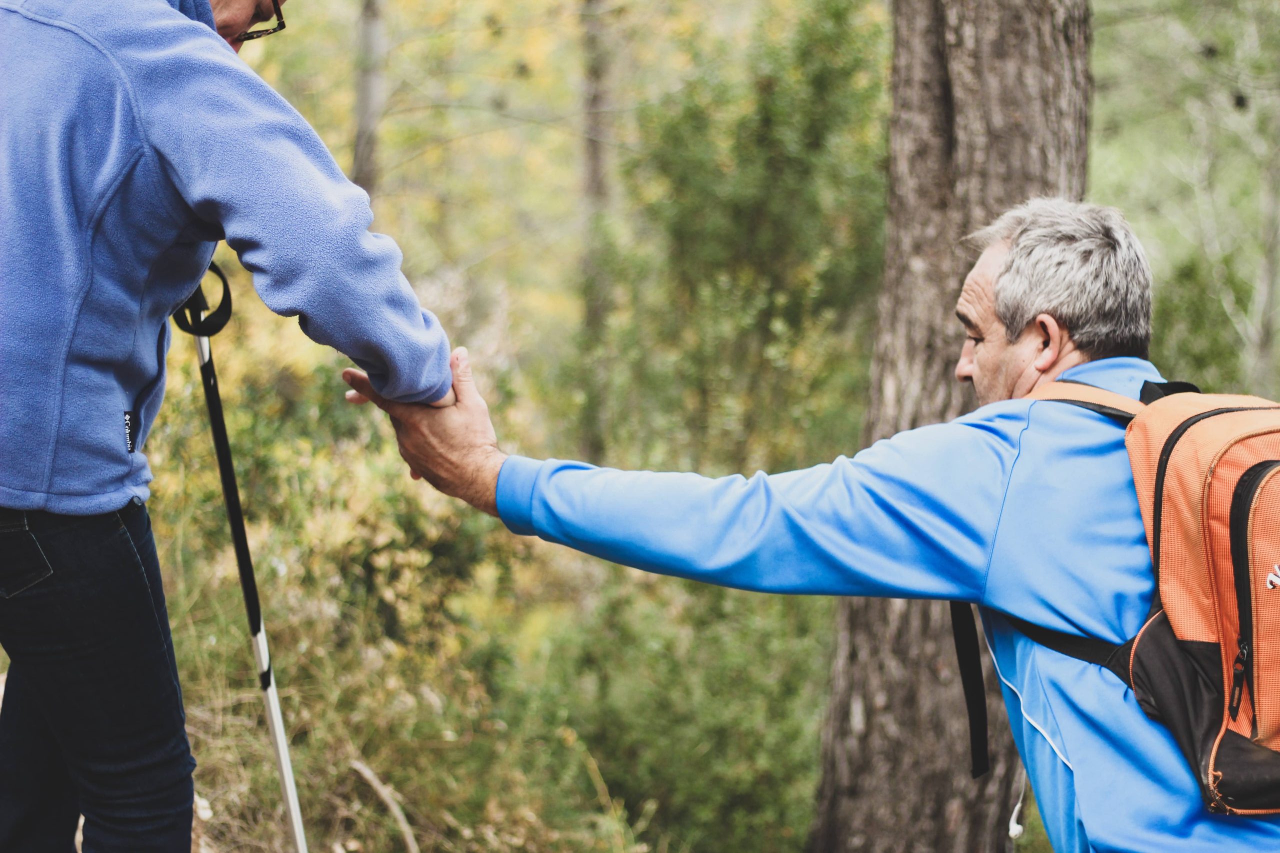 older man hiking offering helping hand